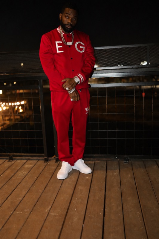 Don Chief in a red Eat Greedy tracksuit on a rooftop at night