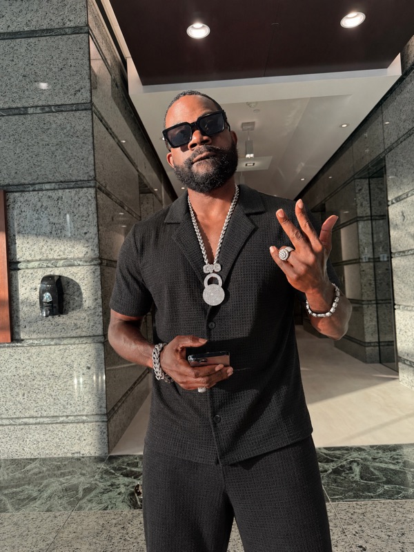 Don Chief in black with a Don Chief chain in a marble lobby
