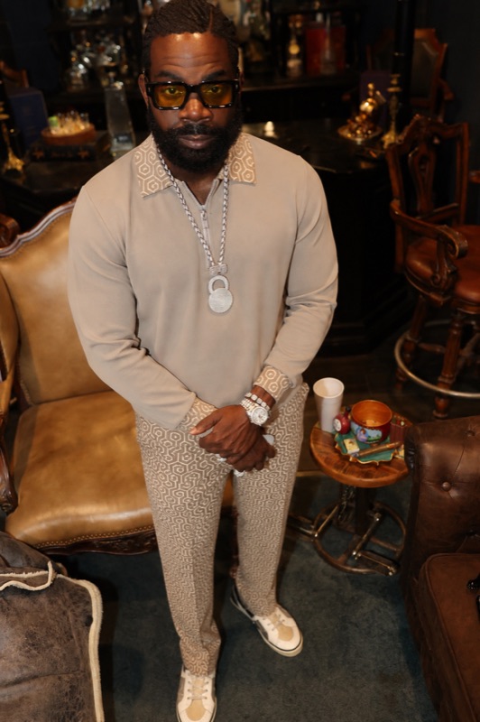 Don Chief in a tan suit and chain inside a cigar lounge