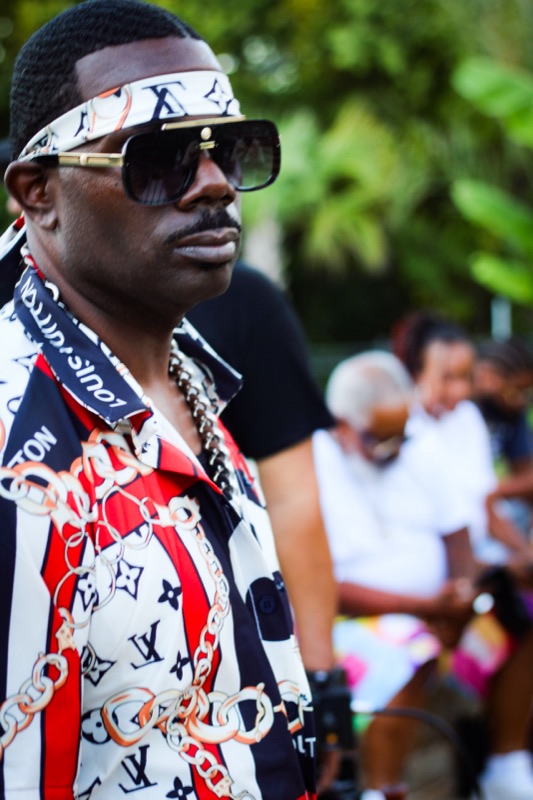 Don Chief outdoors in designer sunglasses and a chain
