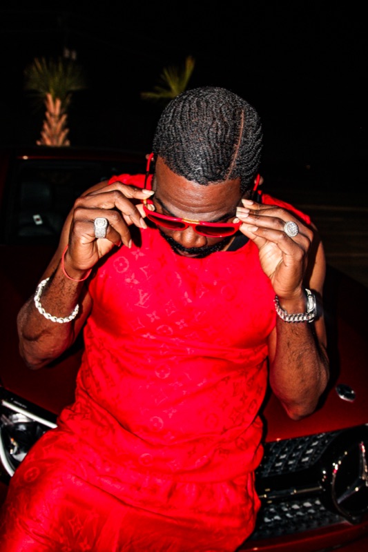 Don Chief in red on the hood of a red car at night